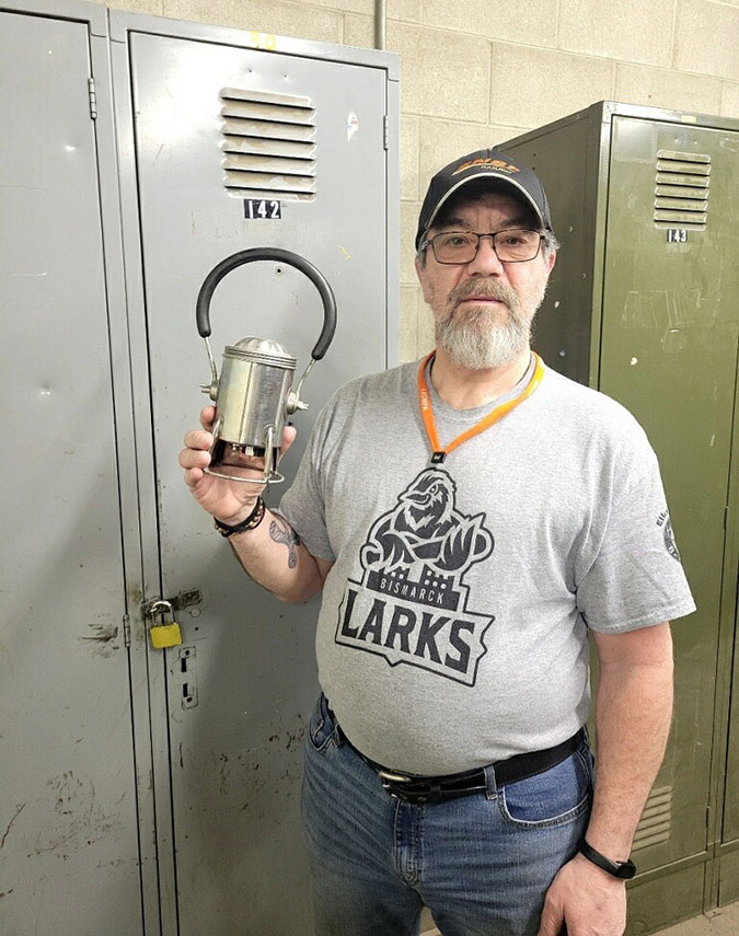 Jeff Kessel standing in front of his locker at work, holding his father&rsquo;s 30-year-old carman lantern 