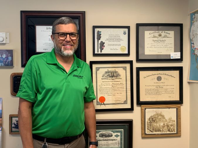Shane Mudge next to a wall of his family’s railroading awards and achievements. Shane Mudge next to a wall of his family’s railroading awards and achievements.