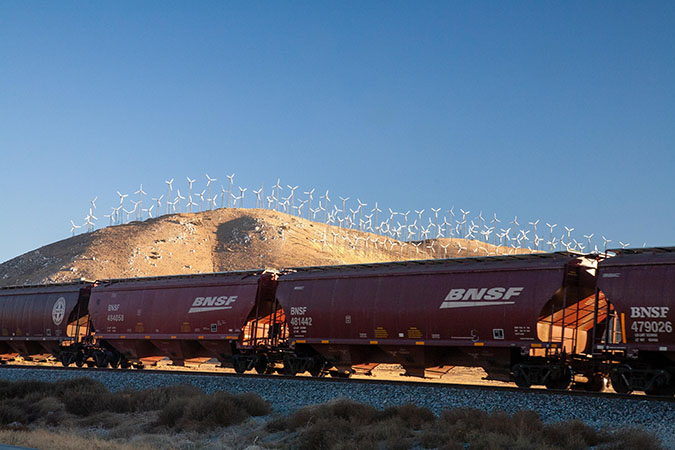 Grain hoppers passing a wind farm